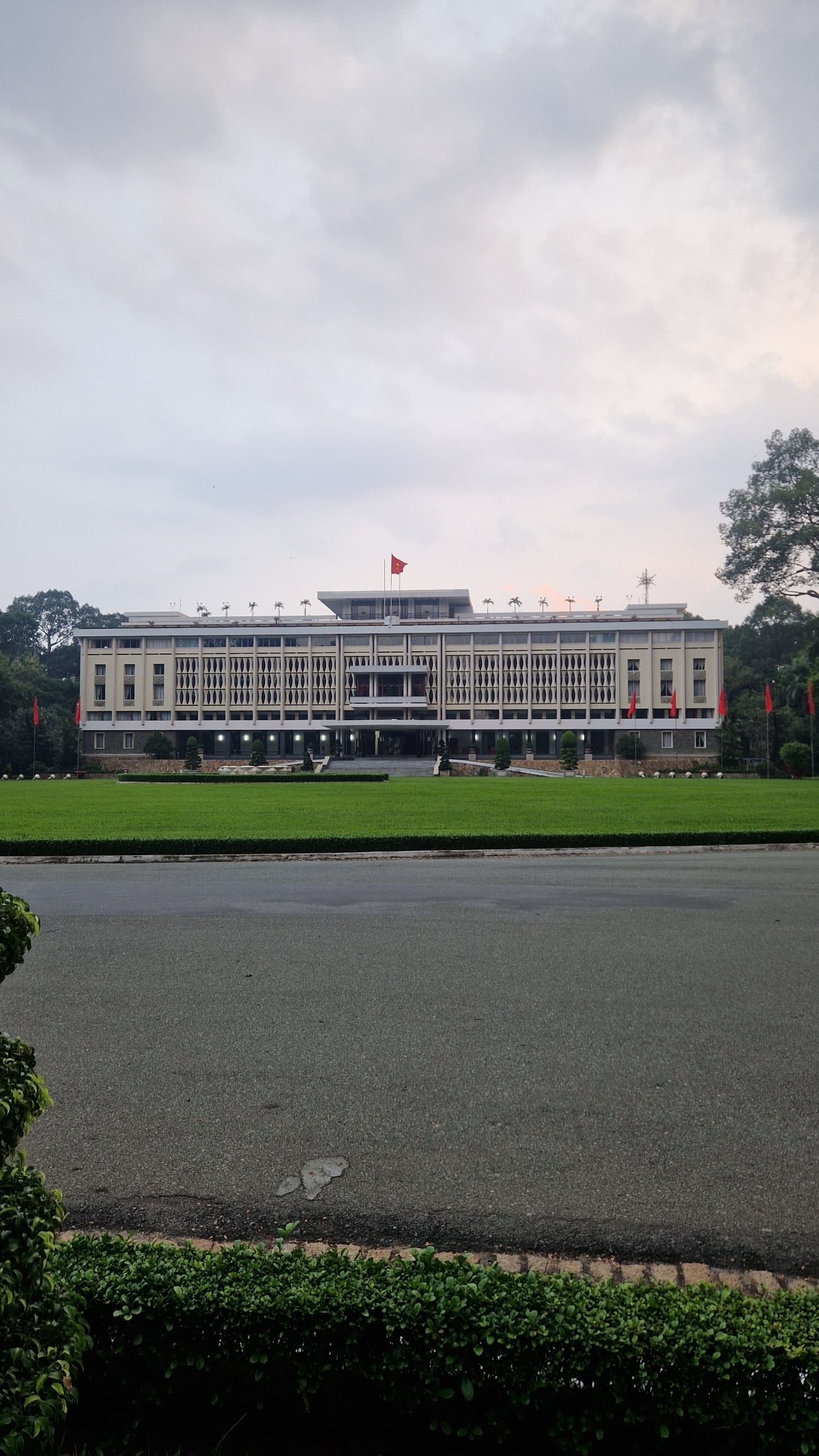 Reunification Palace in Ho Chi Minh City across a green lawn under a cloudy sky