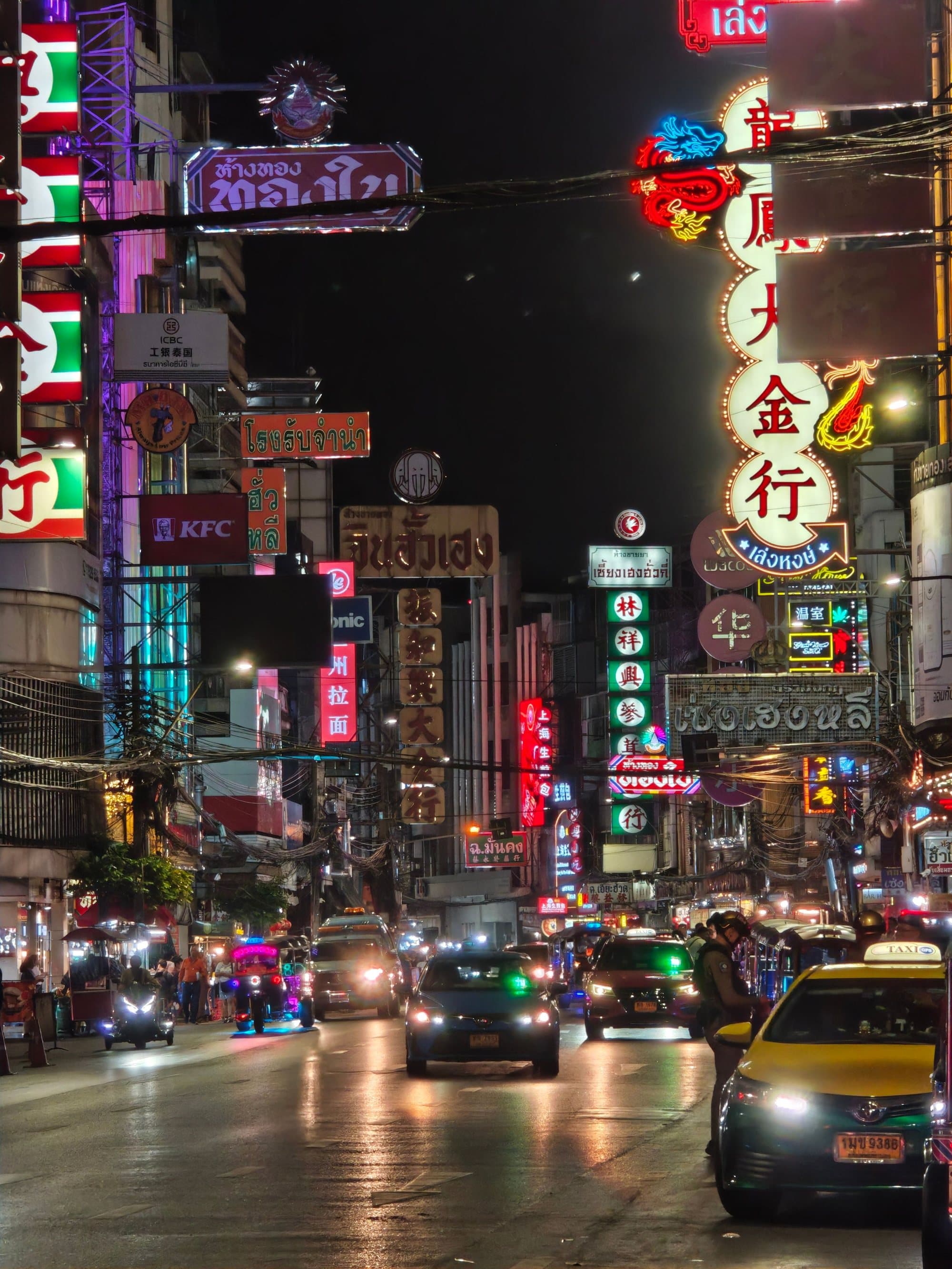 Neon signs above a busy street in Bangkok's Chinatown at night